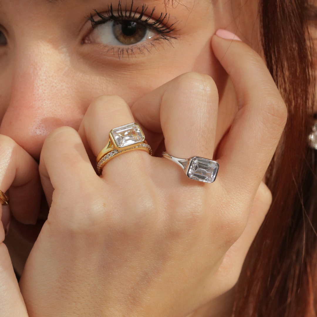 Duo de bague serti clos argent et doré avec un serti est ouest, image de la bague portée sur une main positionnée près de l'oeil du mannequin